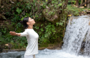 Woman practicing mindful breathing outdoors in a peaceful natural setting