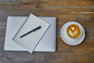 Notebook open on a table with coffee and a pen, morning journaling routine